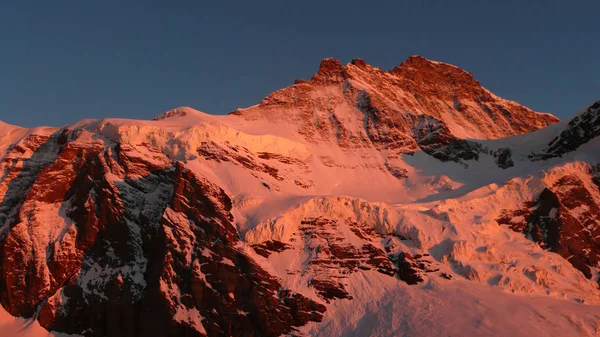 the north face of Jungfrau mountain peak in warm red evening light in the Swiss Alps above Grindelwald