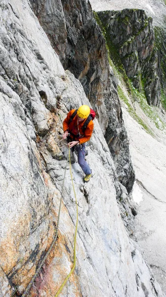 rock climber on a hard alpine route in the Alps of Switzerland placing mobile protection