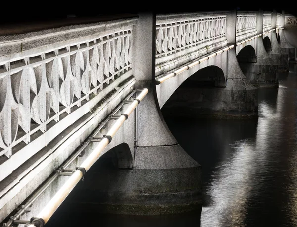 ダウンタウン チューリッヒ低キーの効果で夜の穏やかな川に架かる古い石橋 — ストック写真
