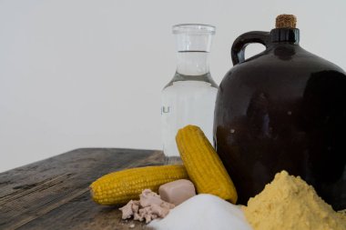 Cob tıpa ve rustik ahşap bir masa üzerinde kaçak içki mısır likörü yapmak için malzemeler ile kil yarım galon sürahi