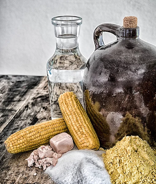 A clay half gallon jug with cob stopper and the ingredients for making moonshine corn liquor on a rustic wooden table