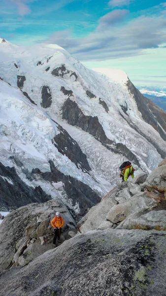 mountain guide and a male client on a rock and snow ridge heading towards a high summit in the French Alps near Chamonix