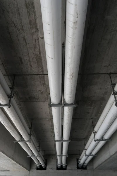 Große industrielle Abwasser- und Wasserleitungen unter einer Betonbrücke — Stockfoto