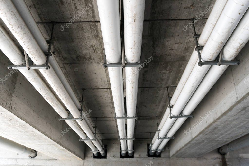 large industrial sewage and water pipes under a concrete bridge