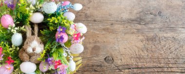 Paskalya çelenk renkli yumurta ve çiçek ve giyen bir tavşan...