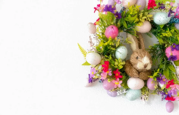 Pasen krans met kleurrijke eieren en bloemen en een konijn in de — Stockfoto