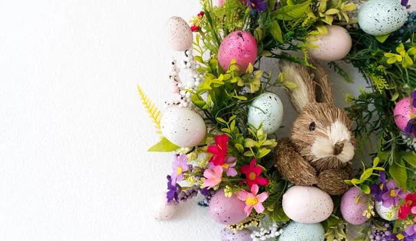 Pasen krans met kleurrijke eieren en bloemen en een konijn in de — Stockfoto