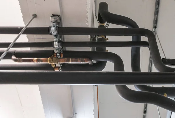 Système de tuyaux métalliques et plastiques sur le plafond de la cave d'un appartement — Photo