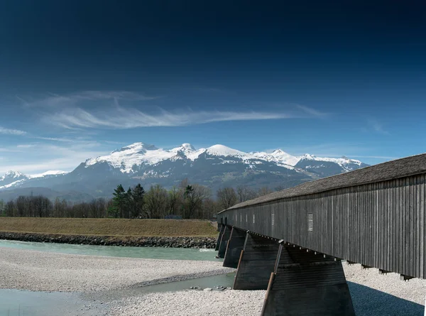 Historic wooden covered bridge across the Rhine with mountain la — Stock Photo, Image