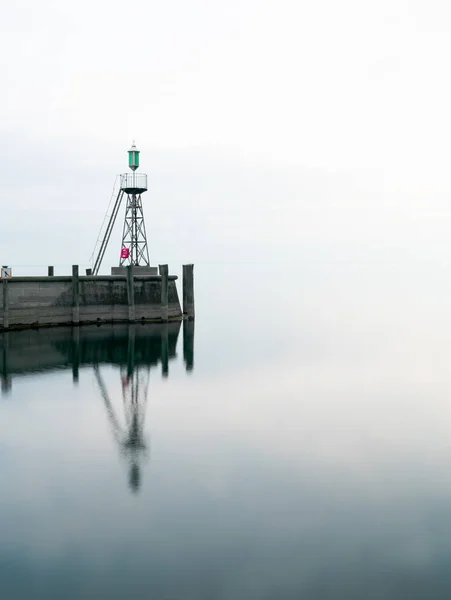 Signal ljus och hamn vägg på lugna sjö vatten under en overca — Stockfoto