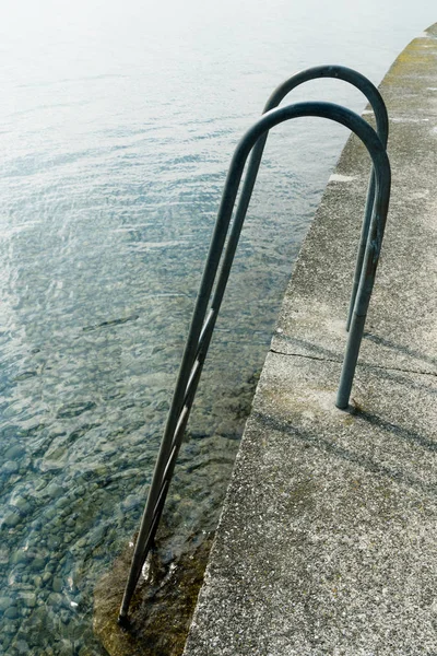 Tall long curved metal stairs leading from a harbor wall down in — Stock Photo, Image