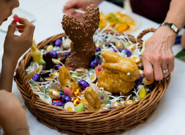 Veel handen bereiken voor snoep snoep en chocolade in een Easter Egg basket — Stockfoto