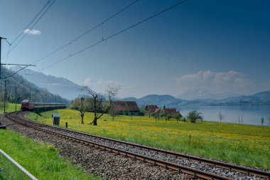 Oberwil, Zg / Swtzerland - 20 Nisan 2019: İsviçre'nin orta kesimindeki Zugersee gölü boyunca hızla giden bir tren