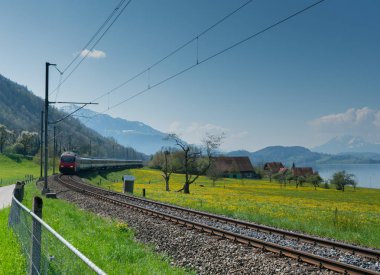 Oberwil, Zg / Swtzerland - 20 Nisan 2019: İsviçre'nin orta kesimindeki Zugersee gölü boyunca hızla giden bir tren