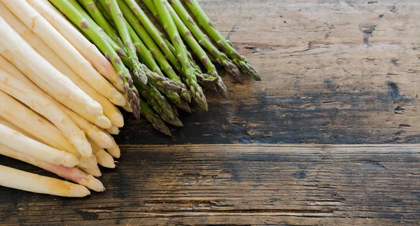 Verse biologische groene en witte asperges op een oud rustiek bruin w — Stockfoto