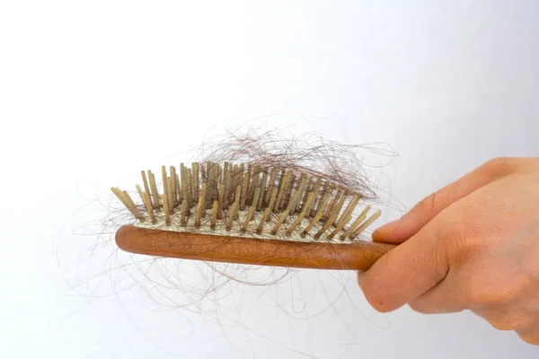 Mujer sosteniendo cepillo de pelo de madera lleno de pelo que se ha caído — Foto de Stock