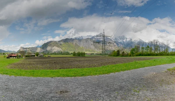 Granja en paisaje montañoso suizo con líneas eléctricas de alta tensión — Foto de Stock