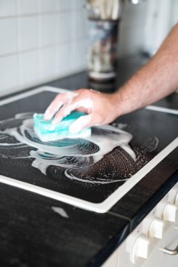 modern ev kocası bir spon ile mutfakta bir soba temizleme