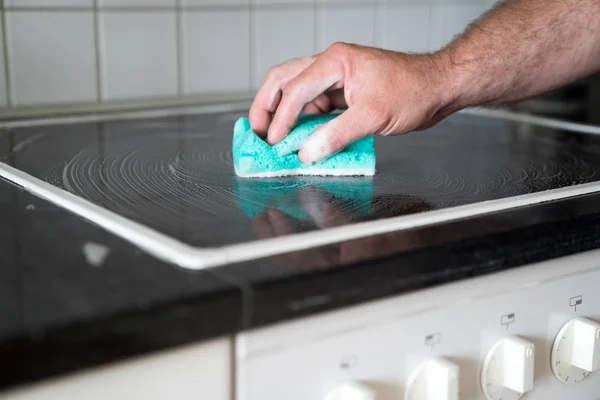 Casa moderna marido limpar um fogão na cozinha com um spon — Fotografia de Stock