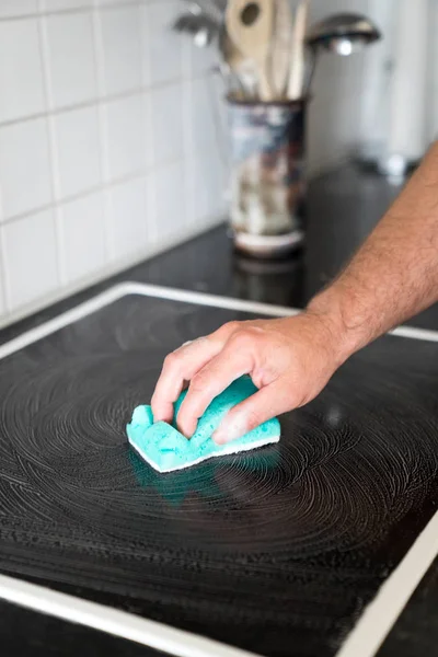 Casa moderna marido limpar um fogão na cozinha com um spon — Fotografia de Stock