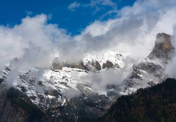 Nevado y nebuloso desierto de montaña bajo un cielo azul claro — Foto de Stock