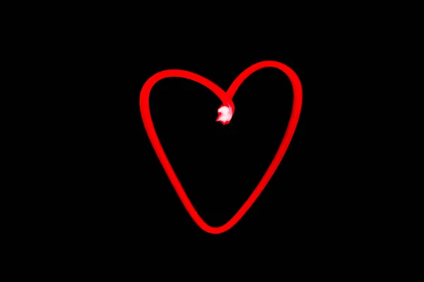 red heart outline light painting in black night sky