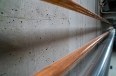 beton bir kiler duvar boyunca uzanan uzun yeni parlak bakır borular