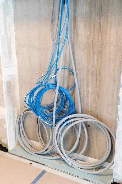 Câbles électriques gris et bleu suspendus sur un mur en spirales et — Photo