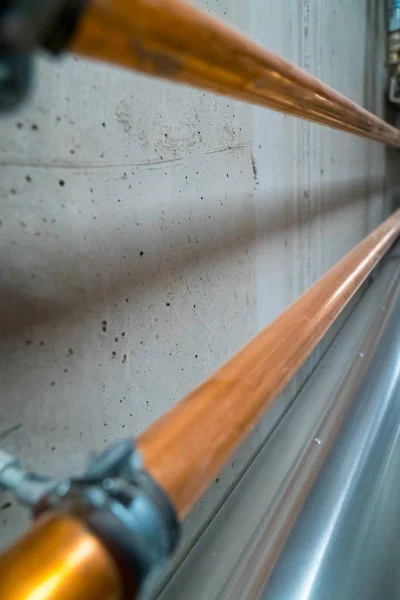 Lange nieuwe glanzende koperen buizen leiden langs een betonnen kelder muur — Stockfoto