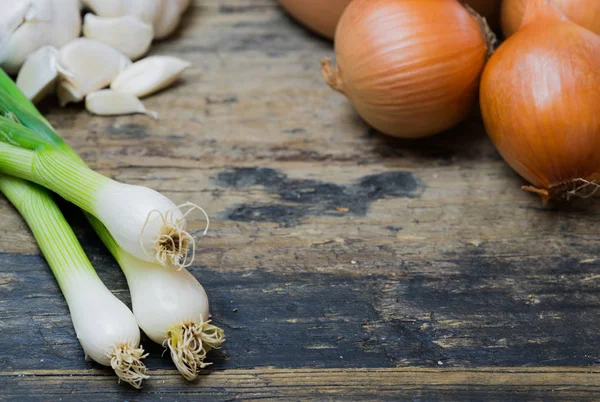 Cipollotti aglio e cipolle marroni su un tavolo di legno rustico — Foto Stock