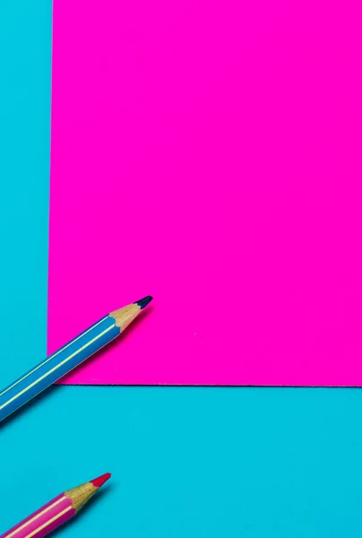 colored pencils on a bright pink and turquoise background