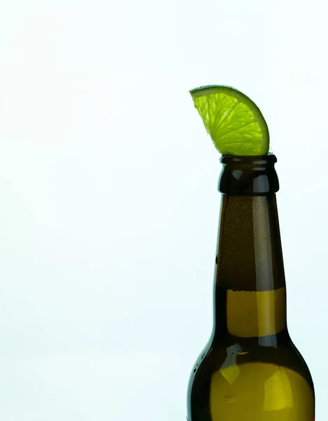 白い背景とコピースペースに緑のライムのスライスを持つ孤立した茶色のビールボトル — ストック写真
