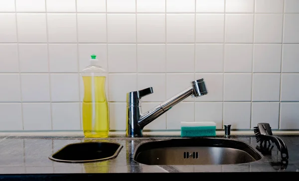 kitchen sink with metal faucet and yellow dishwashing liquid on