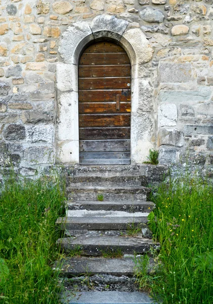 Pequeña puerta de madera en una gruesa y masiva muralla medieval con — Foto de Stock