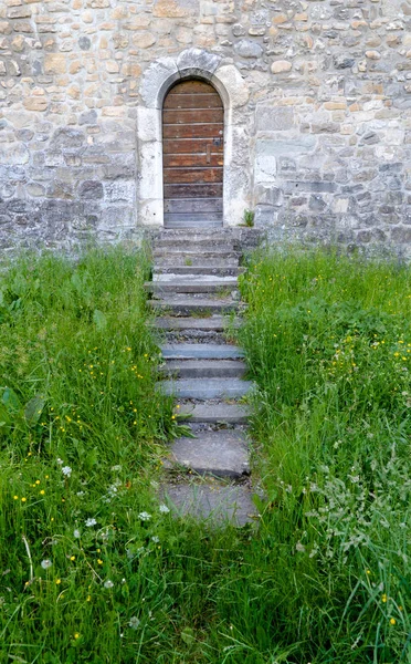 Pequeña puerta de madera en una gruesa y masiva muralla medieval con — Foto de Stock