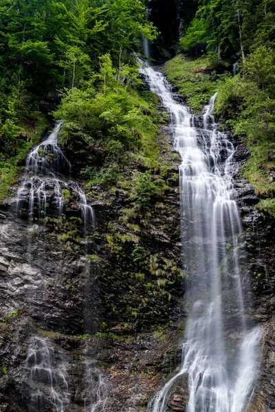 Panorama av högt pittoreskt vattenfall i frodig grönskogs mark — Stockfoto