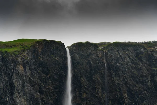 Alta cascata precipita da una scogliera rocciosa ed erba in Svizzera — Foto Stock