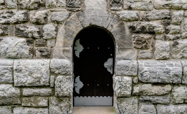 Puerta de madera masiva en una pared de piedra hecha de grandes bloques de granito — Foto de Stock