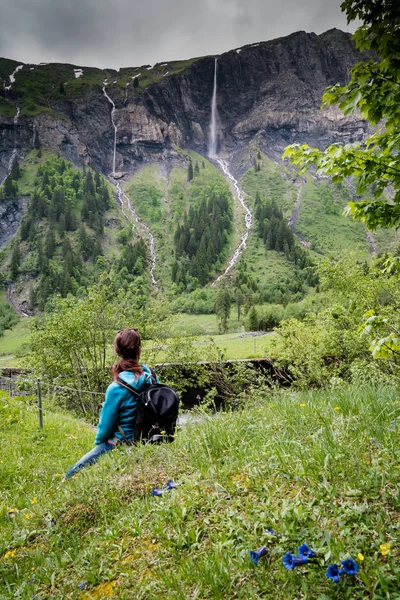 Mujer excursionista mira altas cascadas pintorescas en verde exuberante f — Foto de Stock