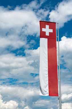 Beyaz cumulu ile etkileyici bir mavi gökyüzü altında İsviçre bayrağı