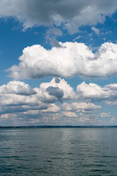 Vertical background of flat anvil-like cumulus clouds in blue sk — Stock Photo, Image