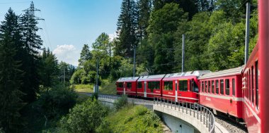 kırmızı dar ölçer bir kıvrımlı St üzerinde bir taş köprü üzerinde traincrossing