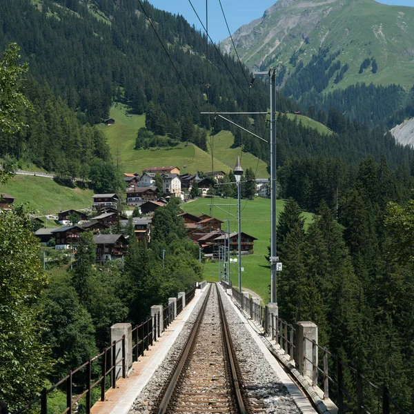 narrow gauge railroad tracks lead over the long bridge of the Langwies Viaduct in the Swiss Alps near Arosa