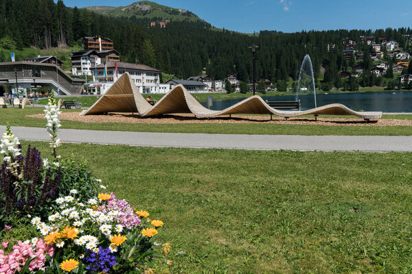 туристы наслаждаются летними мероприятиями на берегу озера в Аросе с железнодорожным и кабельным вокзалом в фоновом режиме
