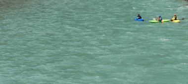 Üç kayakers mavi bir dağ nehirde kürek çekmeye