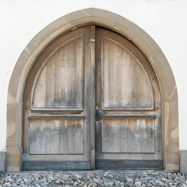 Τεράστια φτερωτή ξύλινη πόρτα σε έναν πέτρινο τοίχο με ξύλινη πόρτα — Φωτογραφία Αρχείου
