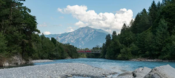 Tren rojo cruza un puente sobre el río Rin en el Alp suizo — Foto de Stock