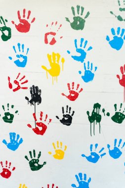 hand prints in many colors on a white wall clipart