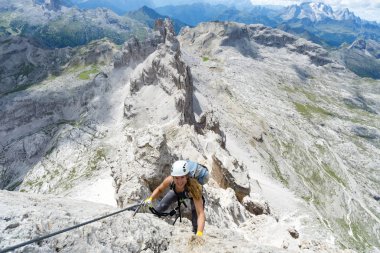 attractive female climber on a steep Via Ferrata in the Italian  clipart
