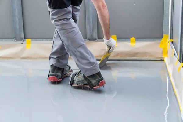 Construction worker renovates balcony floor and spreads watertig — Stock Photo, Image